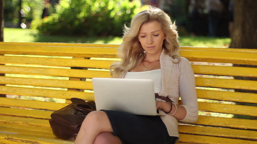 Young business woman with laptop working smiling park bench