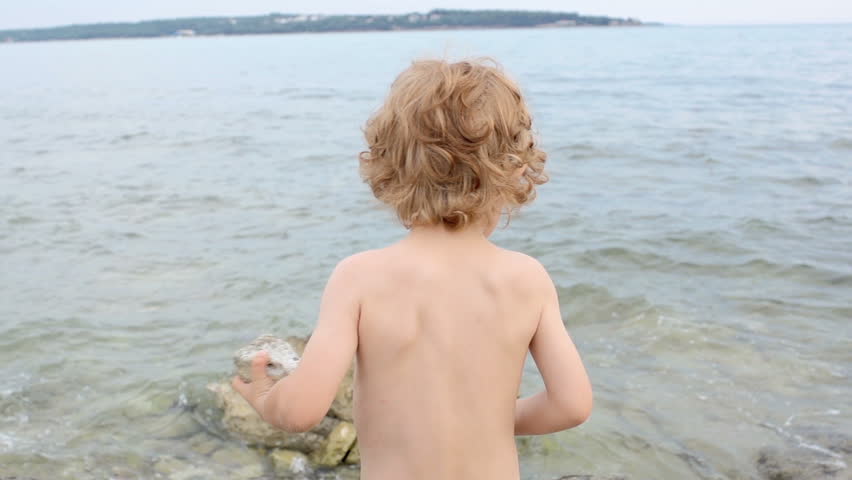 Slow Motion Shot Of A Little Red-Haired Boy Throwing A Stone Into The Sea. Shot