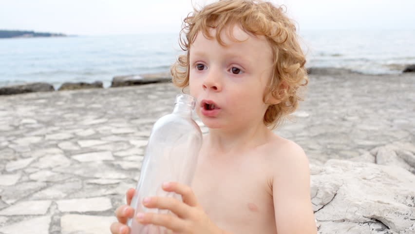 Slow Motion Shot Of A Cute Red-Haired Boy Drinking Water From Glass Bottle