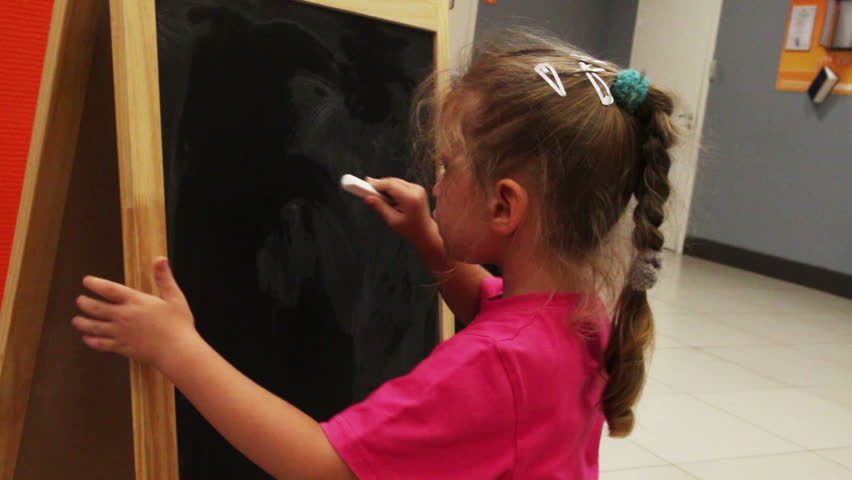 little girl drawing sun with chalk on blackboard