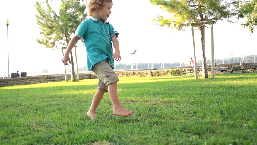 Slow Motion Shot Of A Cute Three-Year-Old Boy Skillfully Kicking A Football Ball