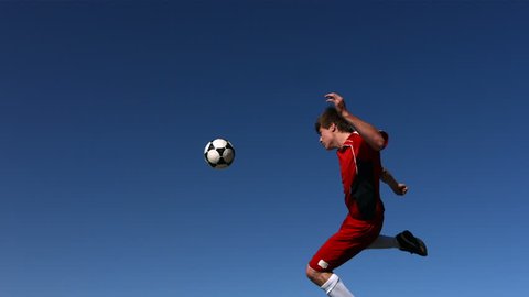 Soccer player kicking ball in mid-air, slow motion