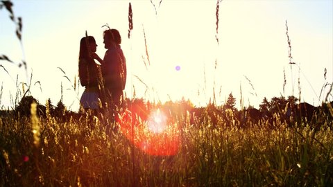 Beautiful Young Couple in Love kiss in a field at sunset