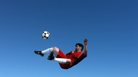 Soccer player kicking ball in mid-air, slow motion