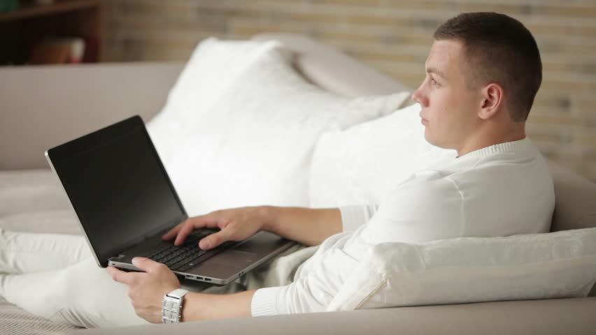 Young man relaxing on sofa and using laptop