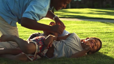 African American dad plays with his sons by tickling them. Medium shot - Βίντεο στοκ
