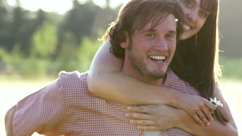 Beautiful Young Couple in Love twirls in a field at sunset in slow motion