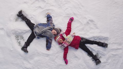 Two kids in winter making snow angels
