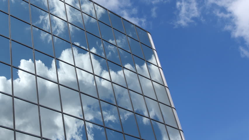Active clouds are reflected in the mirrored windows of an office building. HD