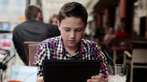 Happy teenager with tablet computer in cafe, steadicam shot
