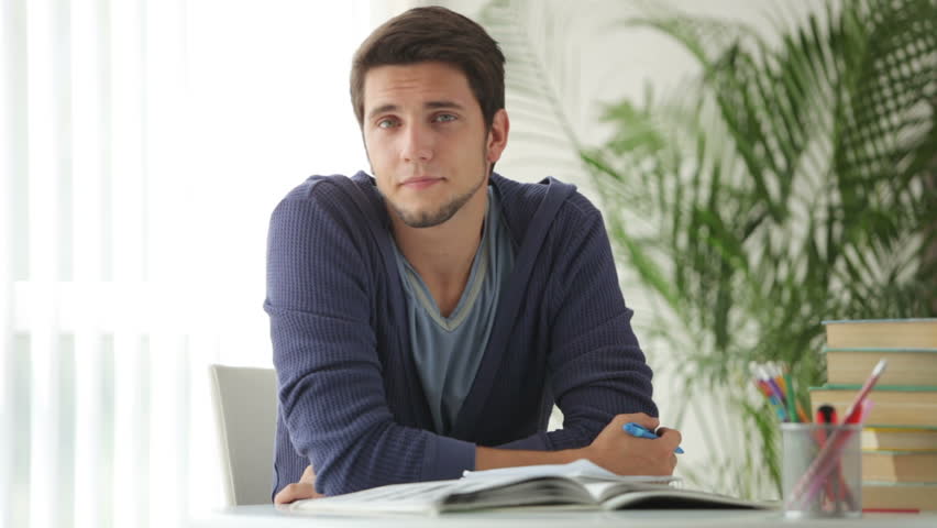 Young man sitting at table and studying with books
