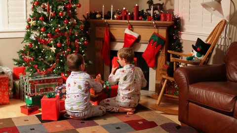 Two young boys run to gifts on Christmas morning Stock Video