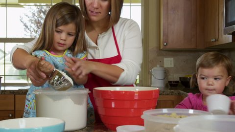 Mother and daughters in kitchen baking cookies together