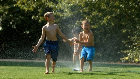 Kids playing in sprinkler, slow motion