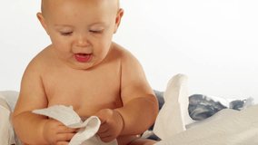 A happy little boy plays with some paper towel and smiles a lot. Medium shot.