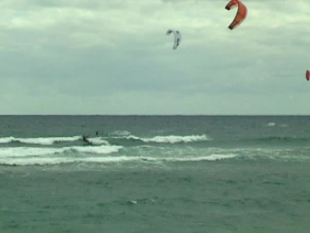Kite surfer boosting a huge air over the small Hawaiian surf.