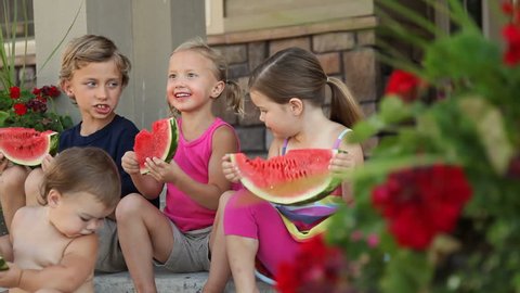 Group of kids sitting on porch eating watermelon