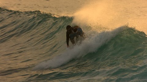 Surfer paddles into wave in late afternoon light, slow motion Stockvideó