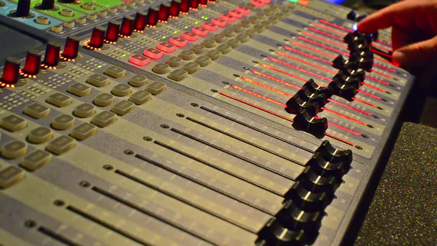 Music records. Operator adjusts equalizer sliders on studio audio mixer. Dark
