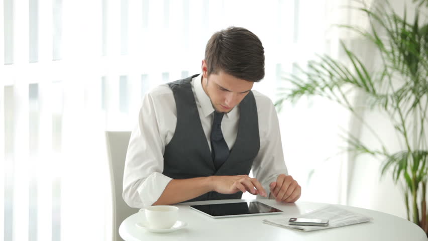 Good-looking guy sitting at table with touchpad and holding credit card