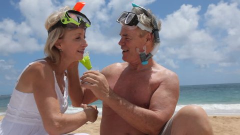 Senior couple helping each other with snorkel gear