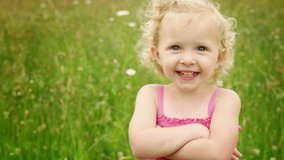 An adorable little girl smiles and then stick her tongue out at the camera. Medium shot