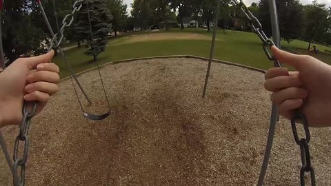 The point-of-view of a girl swinging in a park