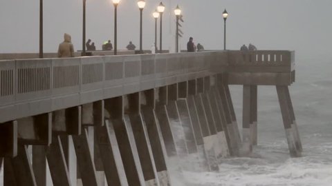 Footage from Hurricane Sandy as it passed by Wrightsville Beach, NC. Tension builds as wind and rain blow sideways.  Shots of pier with waves crashing. Sea foam, water sprays, waves pound beach. Edited Sequence. 
