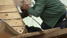 Construction worker nailing metal gilded plate sheet with hummer building church roof close up