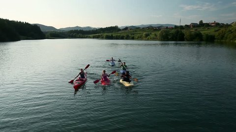 Young people canoeing in the lake towards camera