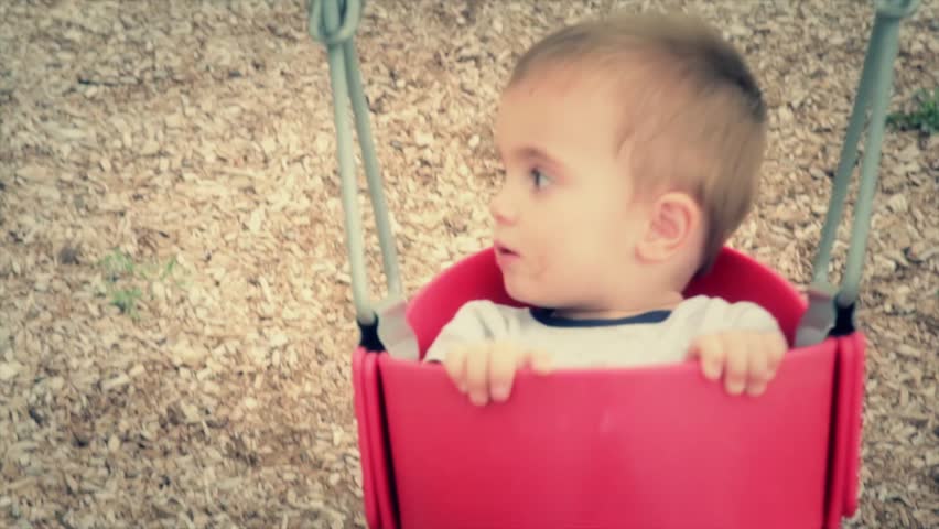 A little boy in a swing at the park