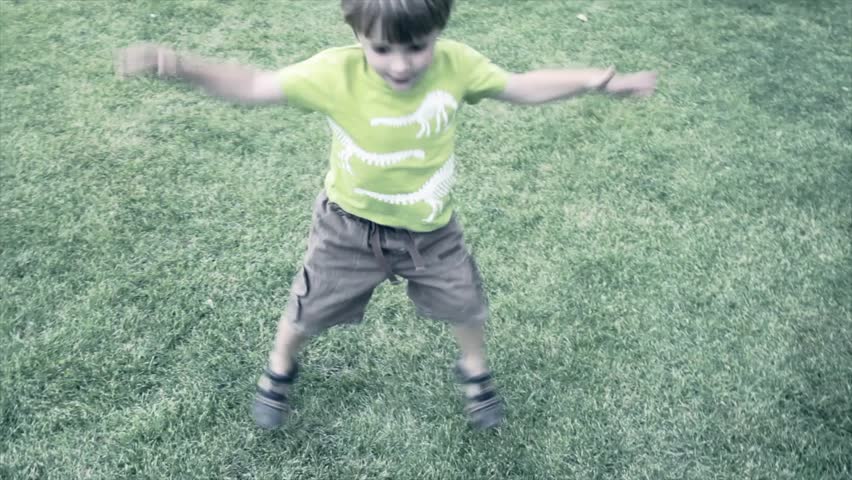 A little boy doing jumping jacks at the park
