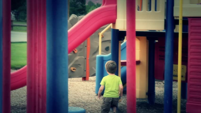 A little boy playing on a slide at the park