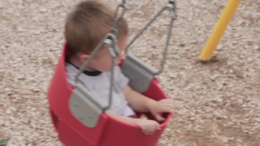 A toddler on the swings at the park