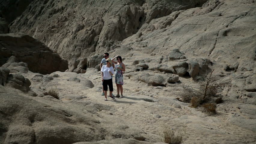 Three tourists goin up the rocky terrain in Safari