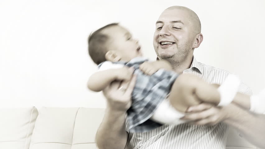 Smiling baby with father sitting on the sofa