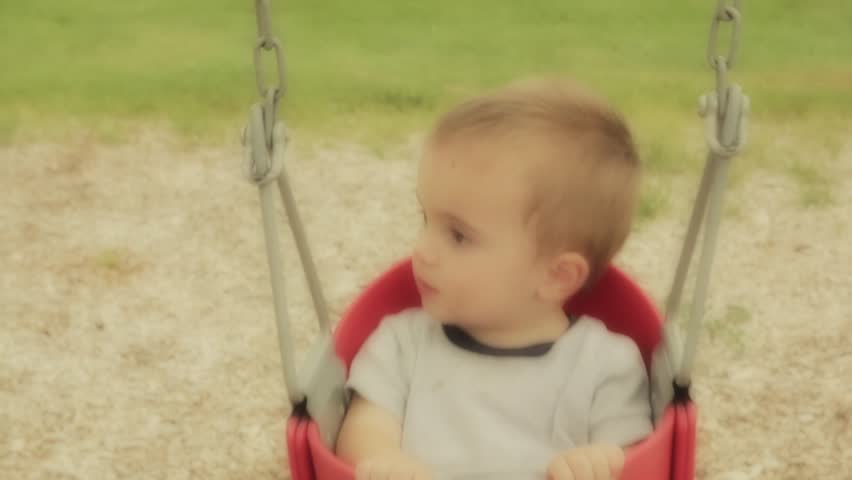 A young toddler in a swing at the park