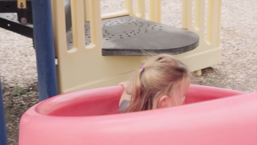 A cute little girl on a slide at the park