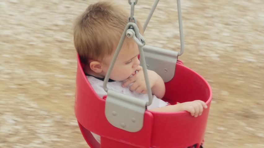 A young toddler in a swing at the park