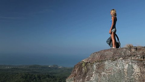 Young lady hiker with backpack reaching top of a mountain