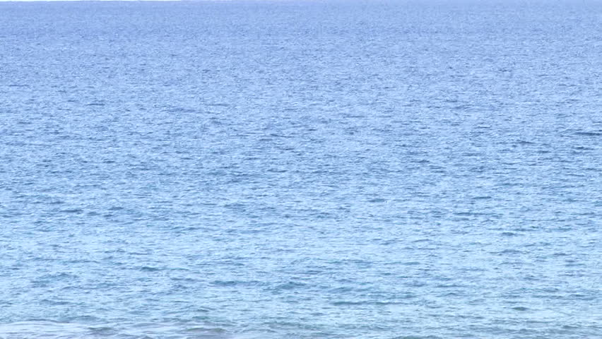 Blue ocean water and empty sky horizon, camera tilt up.