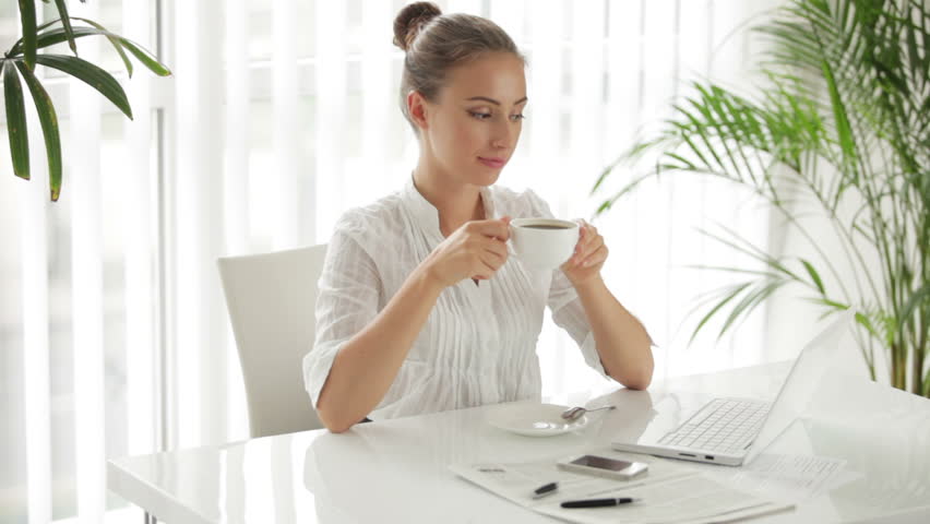 Charming businesswoman sitting at table with cup of coffee