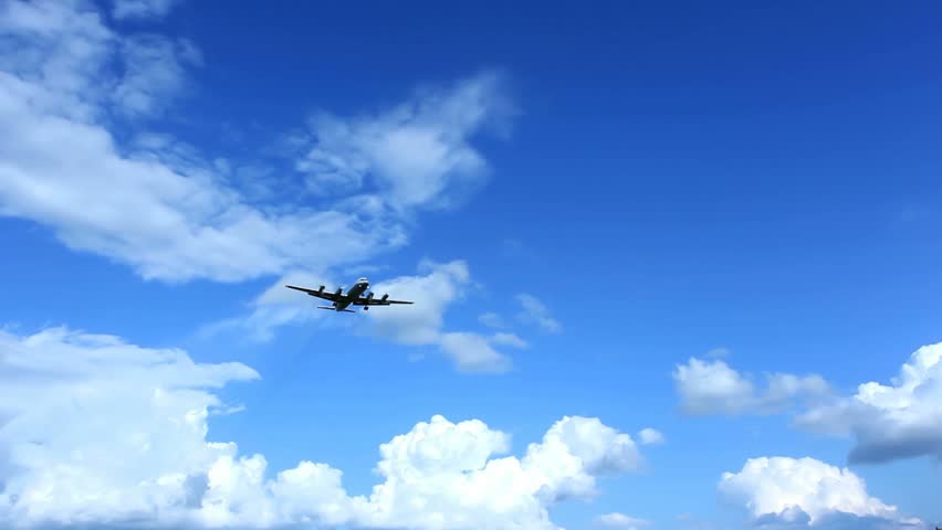 four-engine propeller airplane landing approach across a cloudy sky. Copy-space.