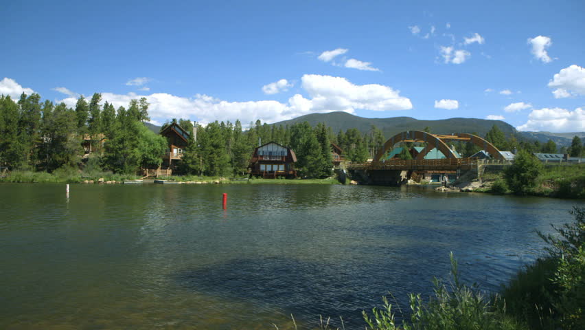 A portion of Grand Lake Colorado accented by a rainbow arch bridge and mountains in the distance.