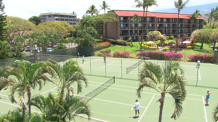 People playing doubles tennis on outdoor courts.