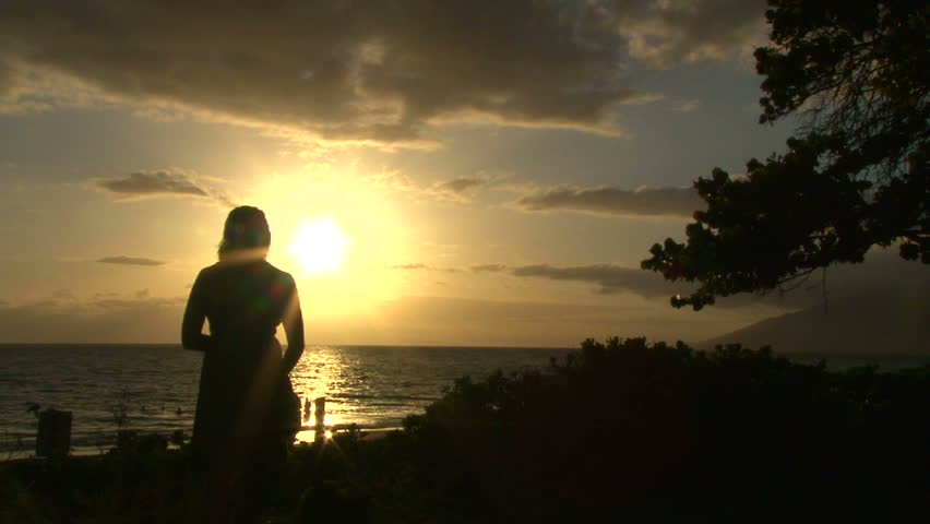 Model released woman standing on beach during sunset in Hawaii.
