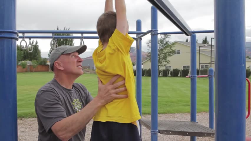 A grandfather playing with his grandson at the park