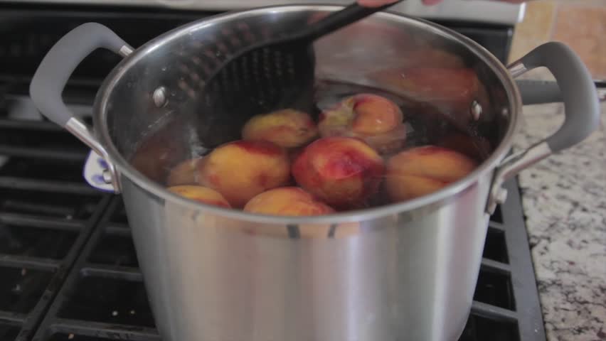 Boiling peaches to remove skin in order to preserve them for food storage