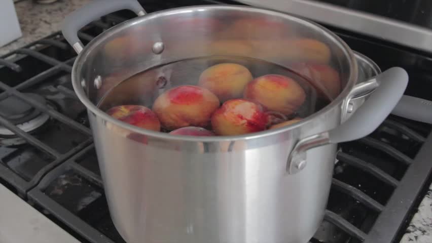 Boiling peaches to remove skin in order to preserve them for food storage