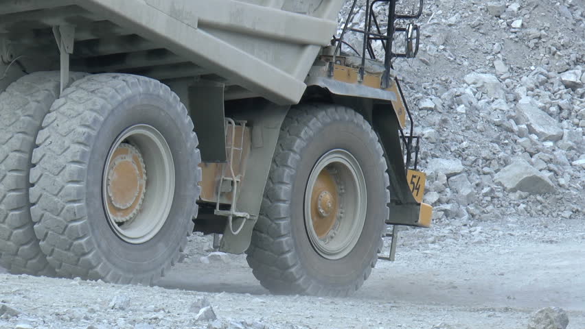 Heavy mining dump trucks moving along the opencast, closeup